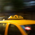 A vibrant yellow taxi with motion blur speeding through a nighttime city street.